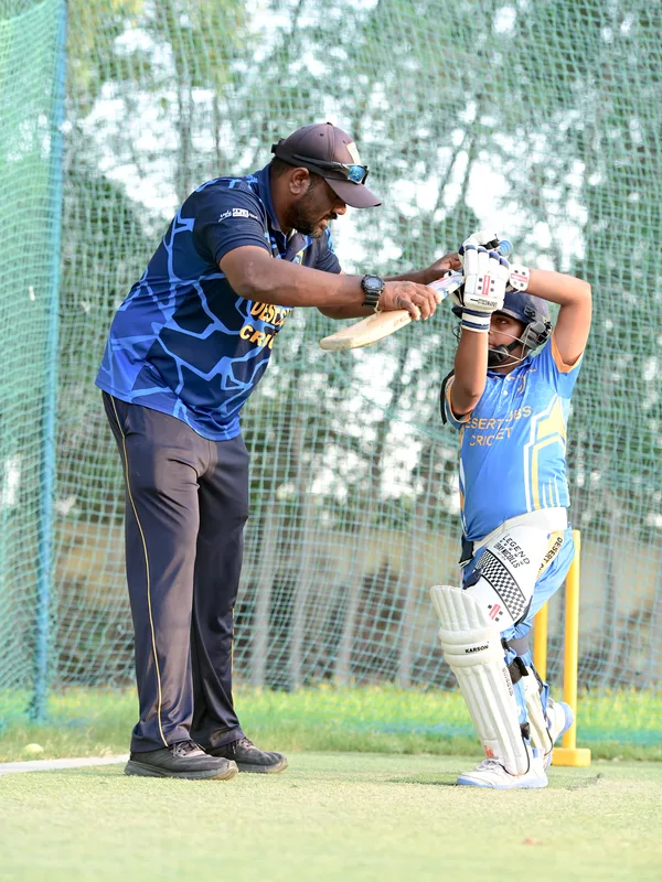 Young SES player practising bat position with direct coach support